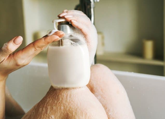 best feminine wash products a close up photo of a woman's hand and a bottle in a tub