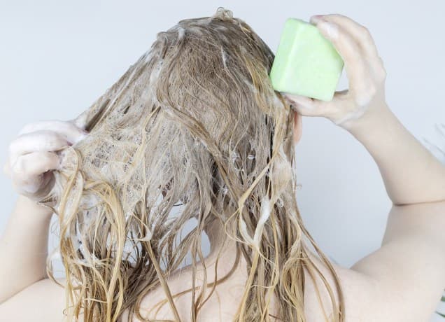 best shampoo bar universal: a woman washing her hair with a shampoo bar