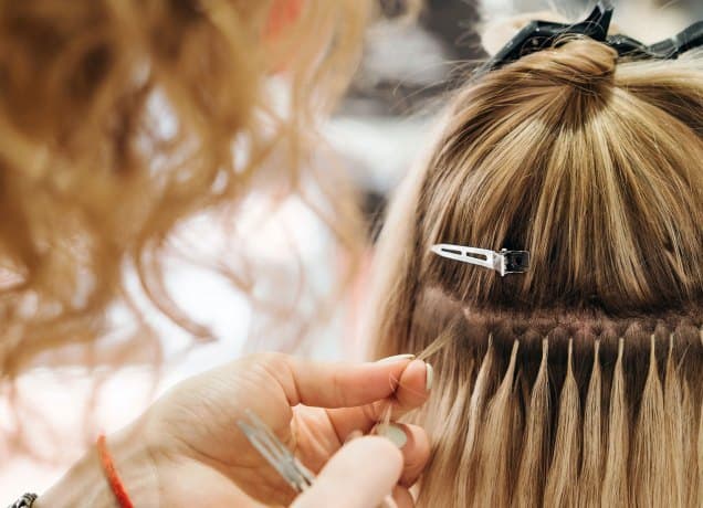 different types of hair extensions a photo of a woman getting extensions done at the salon