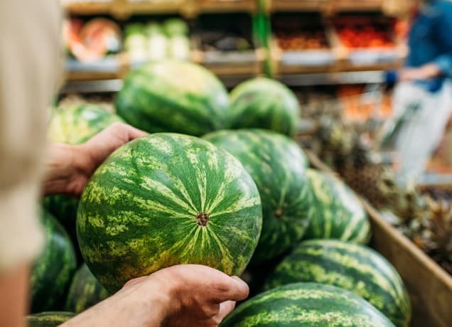 what are the cheapest fruits?: person shopping for watermelon