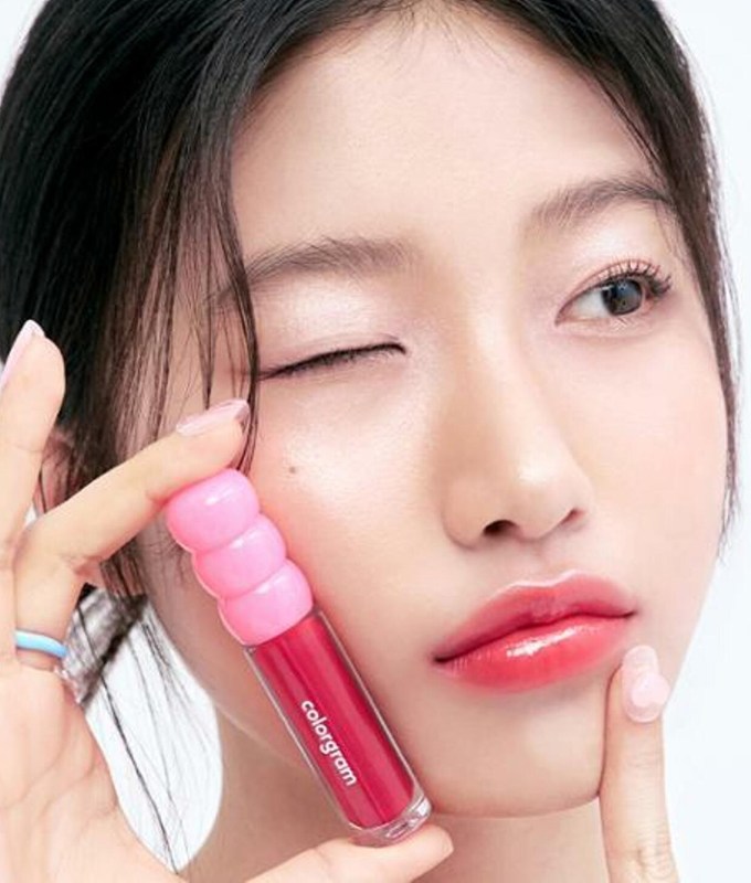 best korean makeup brands colorgram: a woman holding a lip gloss against her cheek