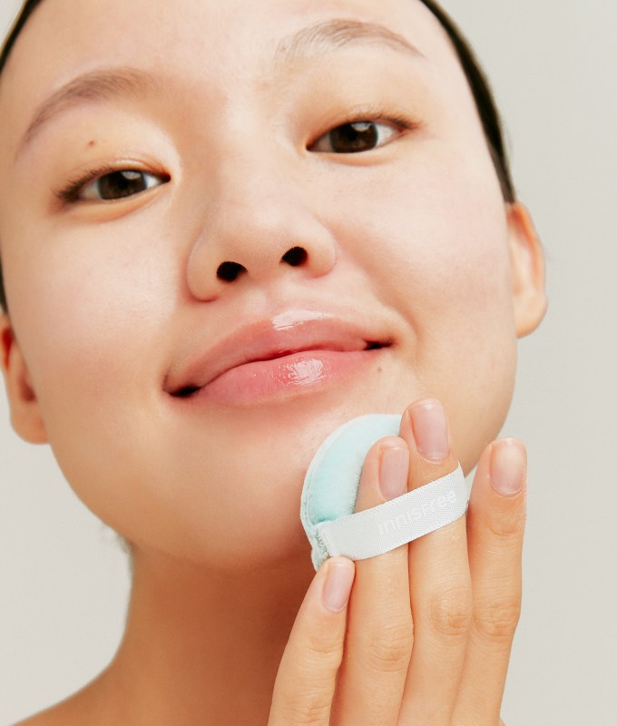 best korean makeup brands innisfree: a woman applying powder to her chin