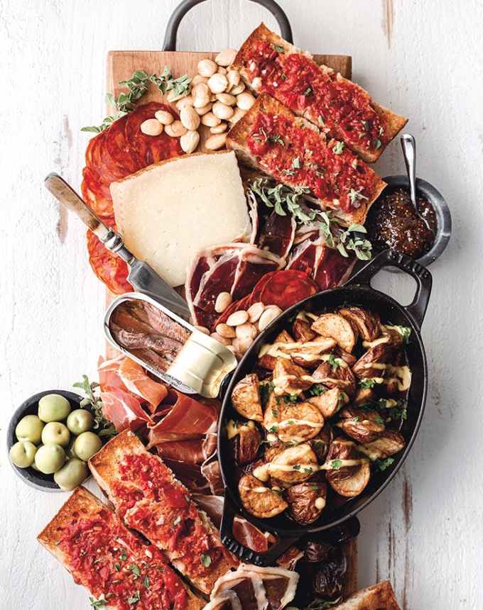 best big-batch recipes: spanish-inspired tapas board with manchego, chorizo, olives, nuts, patatas bravas, pan con tomate and meats