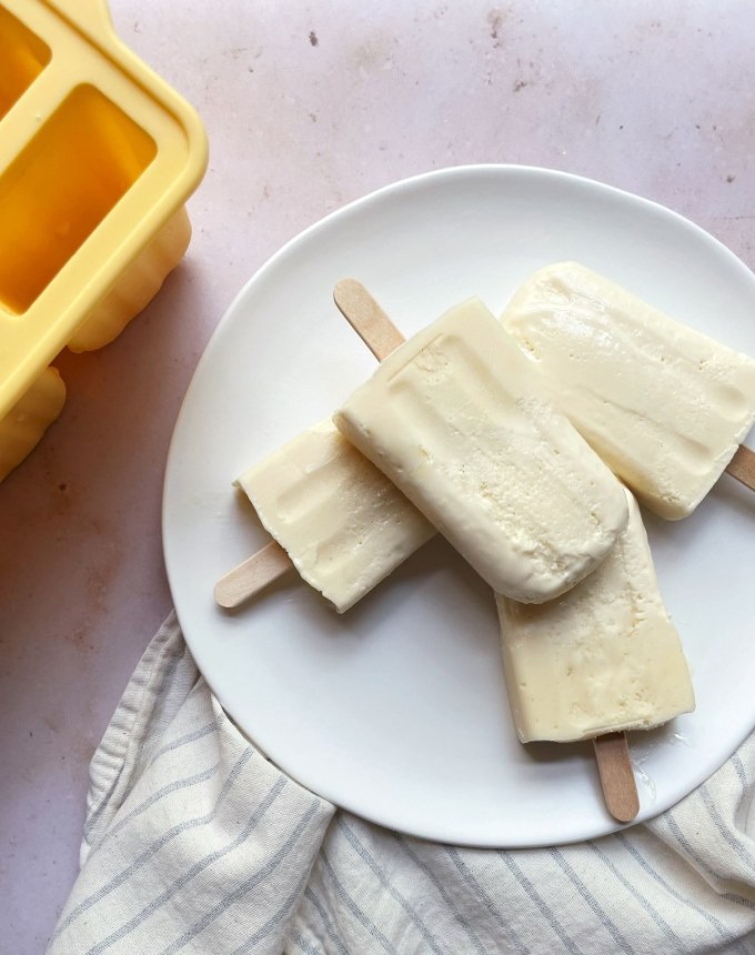 big batch recipes: four key lime pie ice pops on a plate, next to a yellow ice pop mold