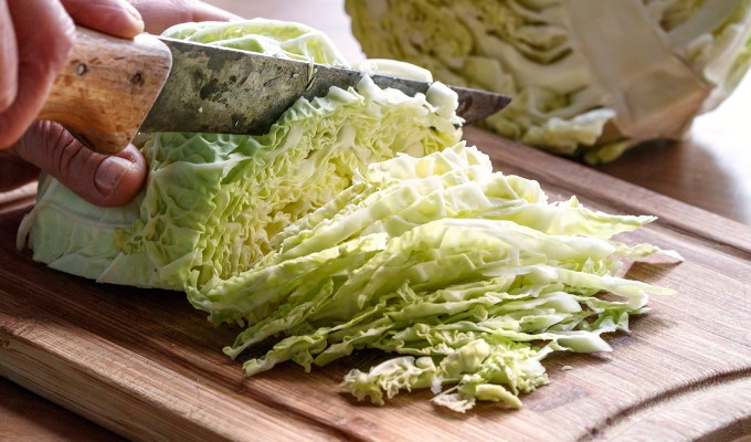 cabbage being sliced on a cutting board