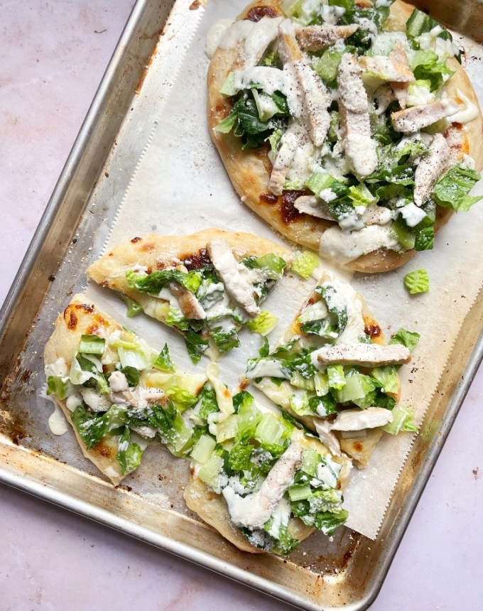 easy lunch ideas: aerial of two chicken caesar salad pizzas on a sheet pan