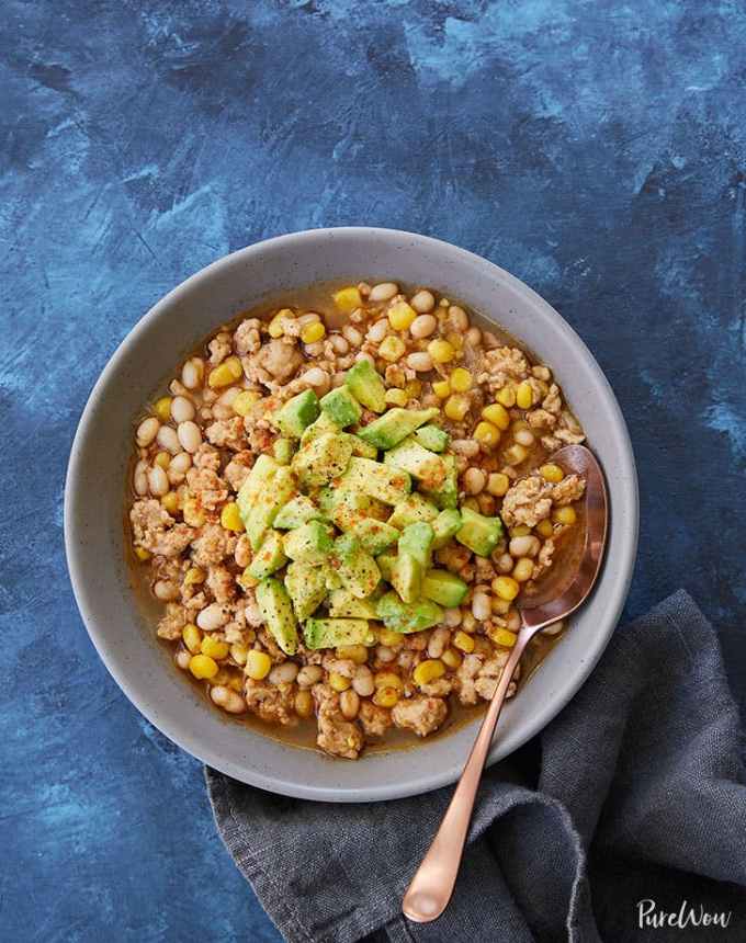 easy lunch ideas: aerial of white turkey chili with avocado in a bowl with a spoon