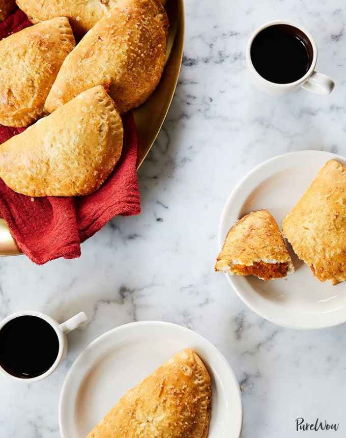 fun things to bake: two plates with pumpkin-filled hand pies, next to two cups of coffee and a basket of hand pies