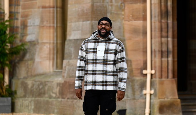 the-traitors-season-2-cast-ranked: A photo of Marcus Jordan in a black adn white plaid shirt standing outside of the castle.