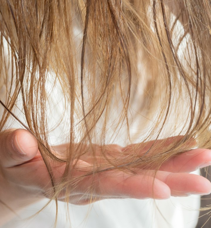 things to stop doing if you have thin hair universal: a closeup image of a woman examining her blonde hair