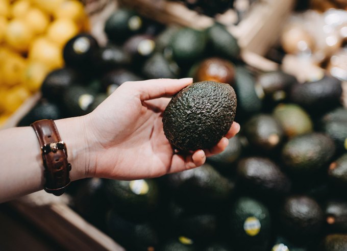 what to cook this week august 19-25: hand holding an avocado at the grocery store