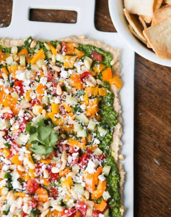 best big-batch recipes: eight-layer hummus dip in a baking dish next to pita chips