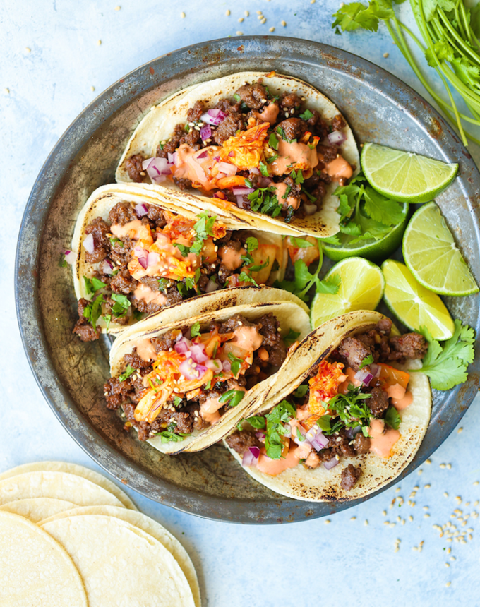 best big-batch recipes: four korean beef tacos on a plate with lime wedges